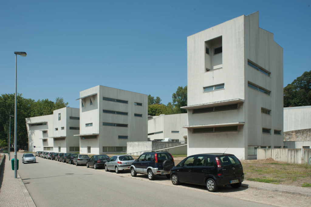 Photo of a series of very modern builds, white rendered block with very brutal square format on the side of a street.