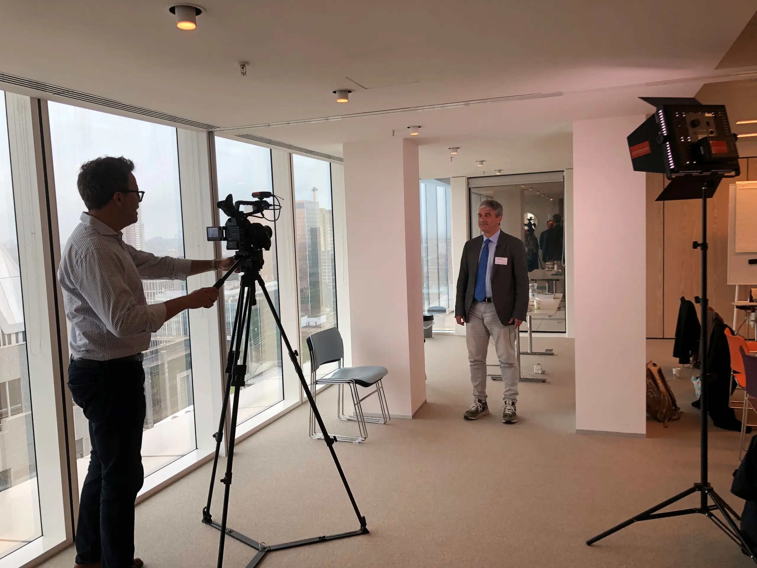 A man behind a large TV style camera filming another man talking