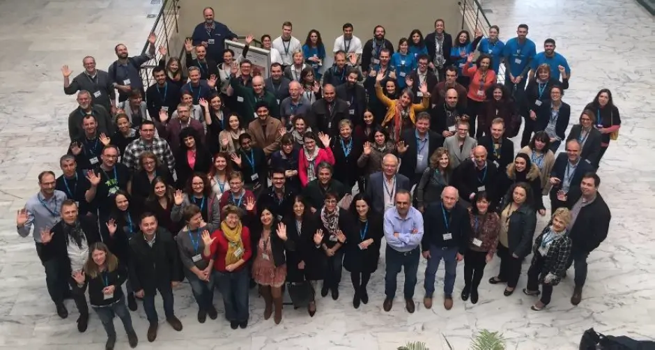 A photo of 100+ people standing in a group in a big open space taken from above