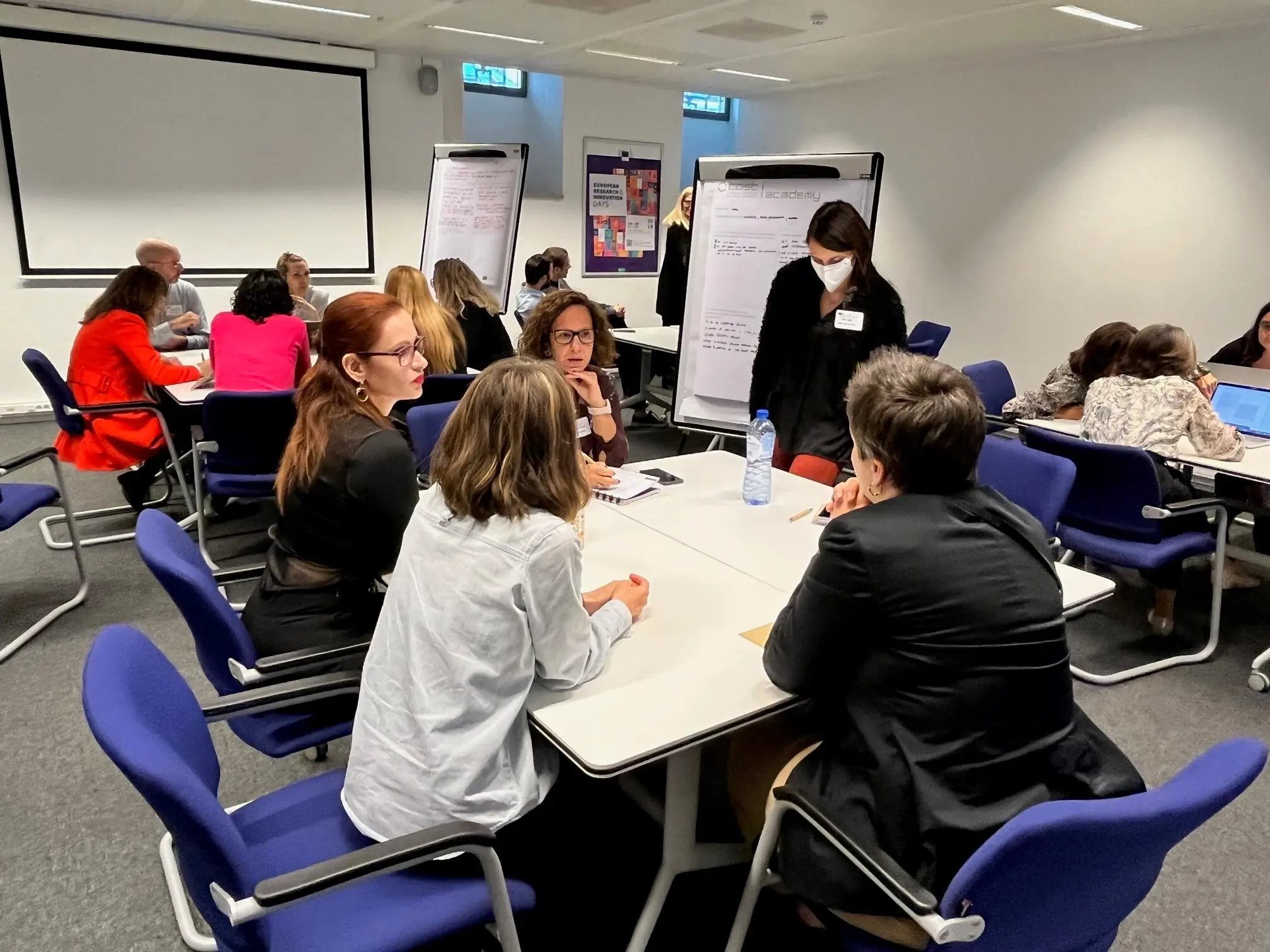 Groups of 5 workshop participants sat at tables in discussion