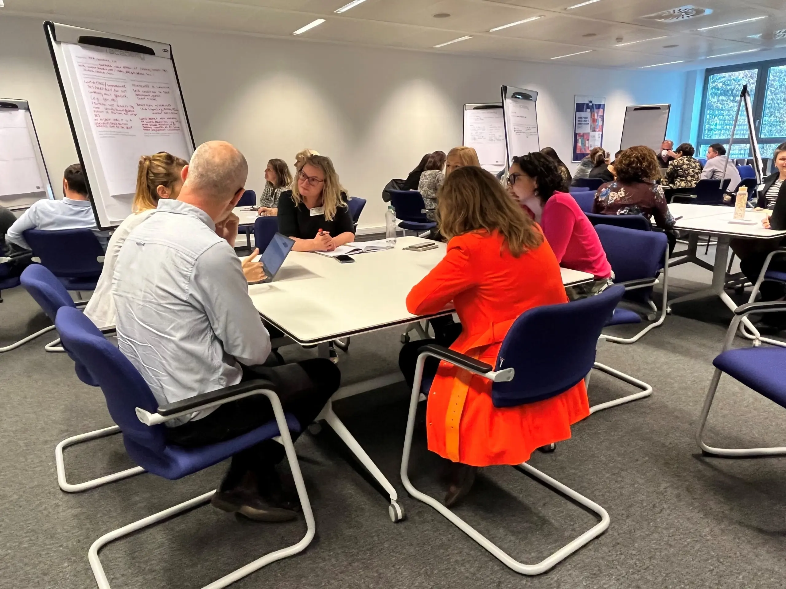 Groups of 5 workshop participants sat at tables in discussion