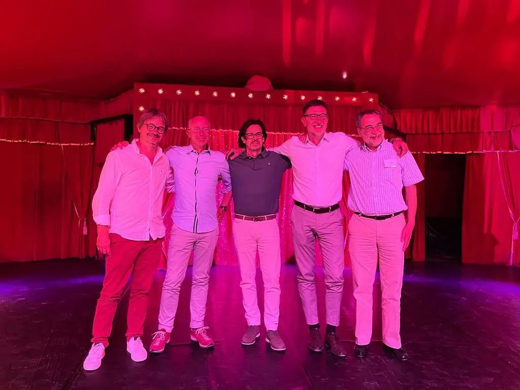 five men standing on stage for a photo during a gala dinner