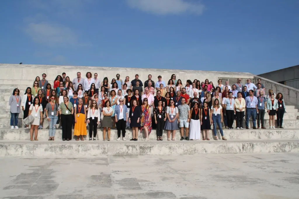 Group photo of a COST Action network standing outside on a very sunny day in Portugal