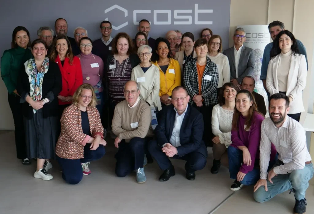 Group photo of the event participants with a COST logo background