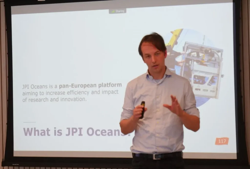 Photo of a young man in white shirt presenting slides.