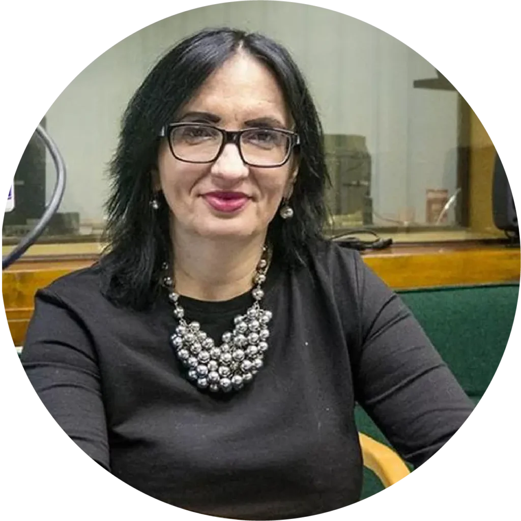 photo of a woman with brown hair, wearing glasses and a shiny necklace