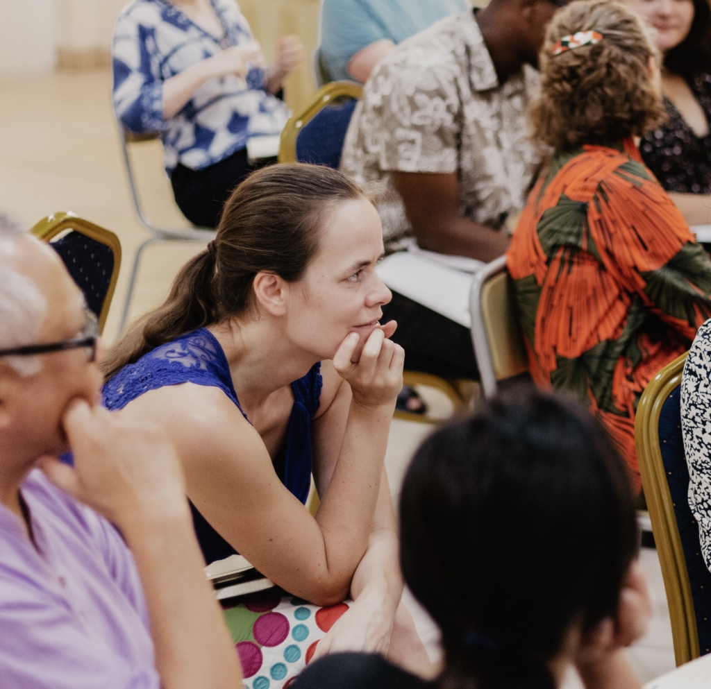 A young woman with a ponytail in the audience of a meeting 